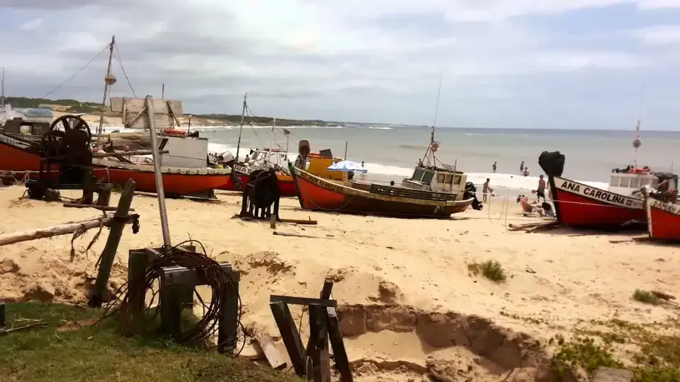 A group of boats are sitting on a sandy beach near the ocean