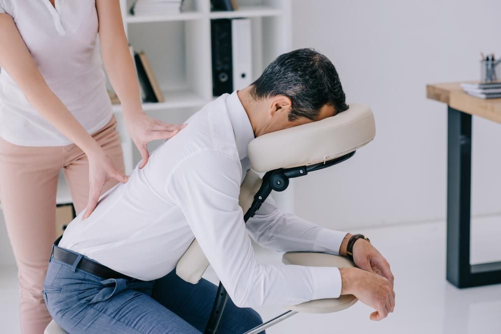 A Man Is Sitting In A Chair Getting A Massage — Mark Coulton Cardiff Physiotherapy Centre In Lake Macquarie, NSW