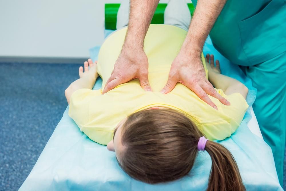 A Little Girl Is Getting A Massage From A Doctor — Mark Coulton Cardiff Physiotherapy Centre In Newcastle, NSW