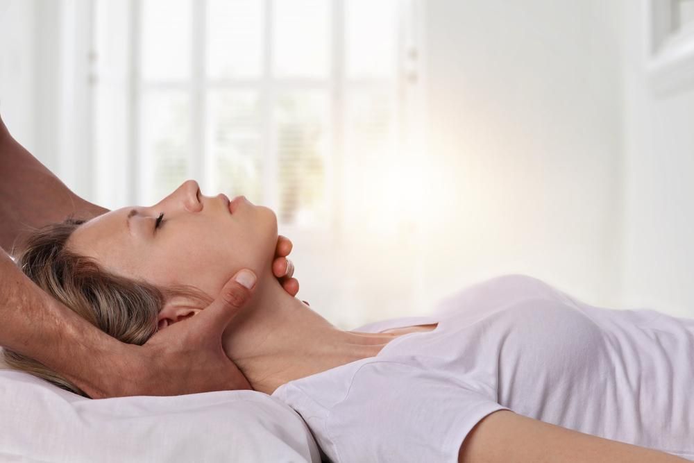A Woman Is Laying On A Bed Getting A Neck Massage — Mark Coulton Cardiff Physiotherapy Centre In Cardiff, NSW