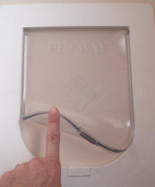 A Finger Lifts the Flexible, Clear Flap of A White Plastic Cat Door — Suburban Security Screens in Currumbin, QLD