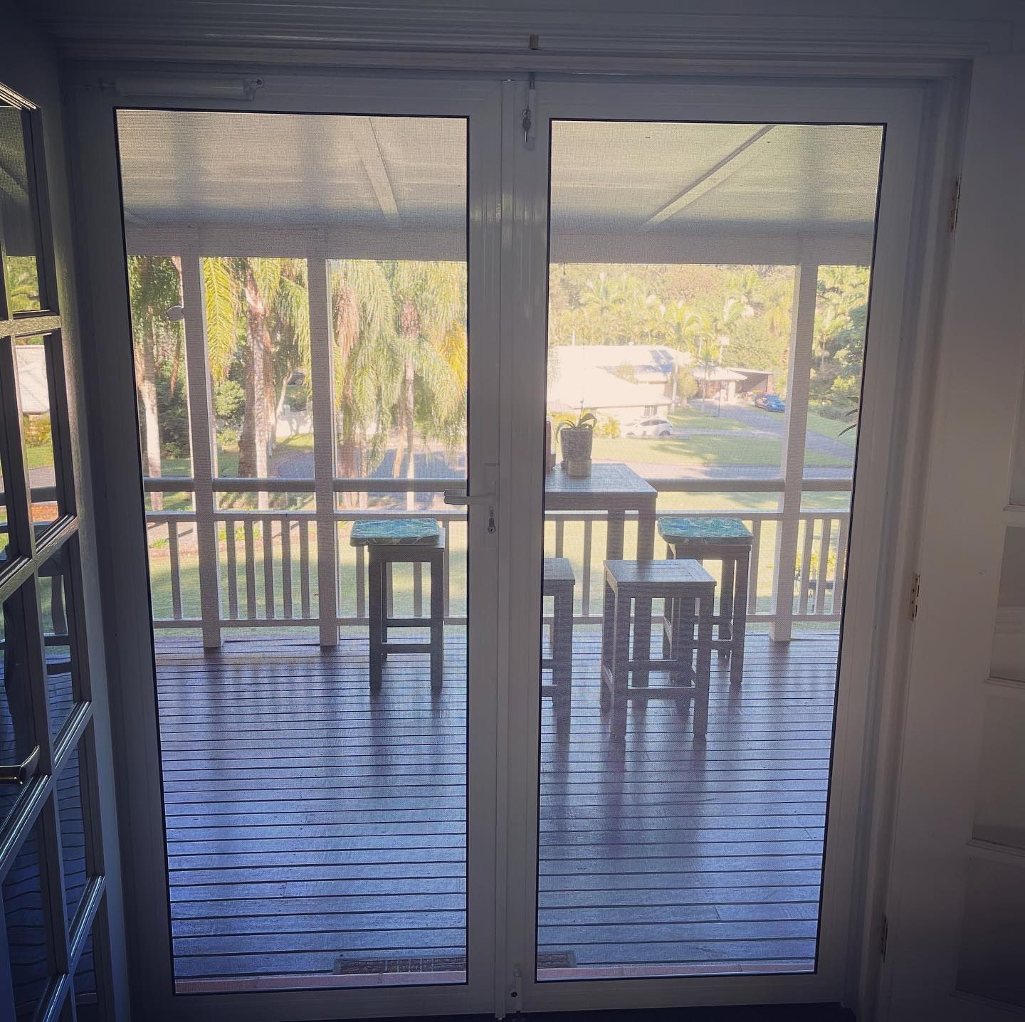 Looking Through Glass Doors Onto a Wooden Deck — Suburban Security Screens in Currumbin, QLD