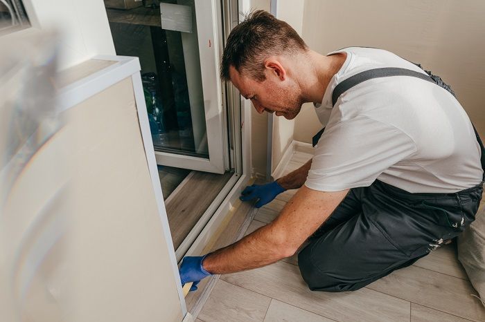 A Worker Install or Seal the Trim Around a White Doorway — Suburban Security Screens in Currumbin, QLD
