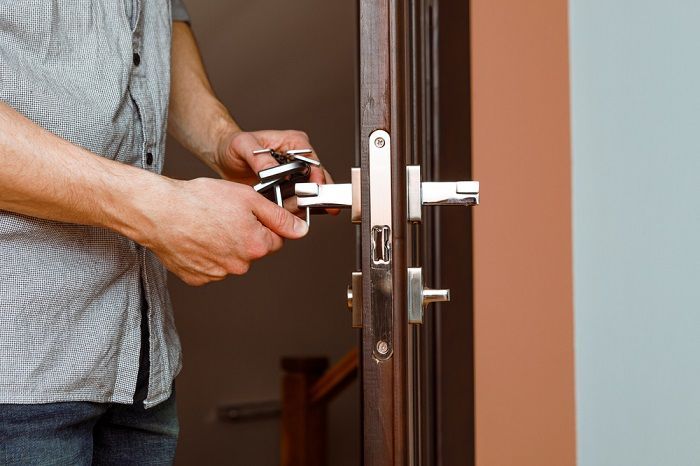 A Person Unlocks a Dark Brown Wooden Door with A Key — Suburban Security Screens in Currumbin, QLD