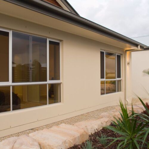 Beige Exterior Wall of a House With Two Windows — Suburban Security Screens in Currumbin, QLD
