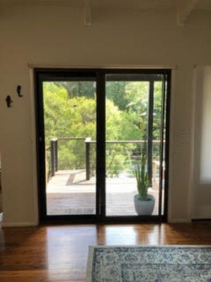 A Sliding Glass Door with A Black Frame Opens — Suburban Security Screens in Currumbin, QLD