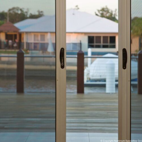 View of a Waterfront House and a Boat Through a Sliding Glass Door — Suburban Security Screens in Currumbin, QLD