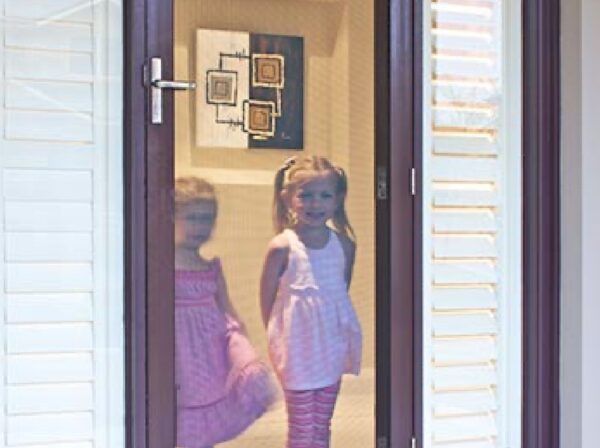 Two Individuals in Pink Outfits Stand Inside a Doorway — Suburban Security Screens in Currumbin, QLD