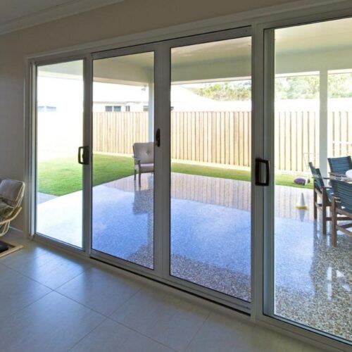Large Sliding Glass Door Opens Onto a Patio With a Chair — Suburban Security Screens in Currumbin, QLD