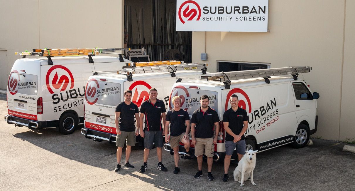Five Employees and A Dog Stand in Front of Three White Suburban Security Vans — Suburban Security Screens in Currumbin, QLD