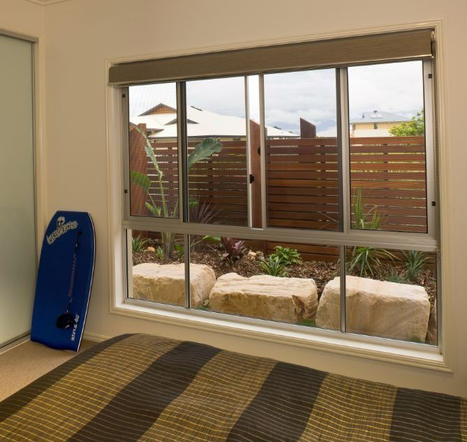 Bedroom Interior With a Striped Bed, a Blue Bodyboard — Suburban Security Screens in Currumbin, QLD