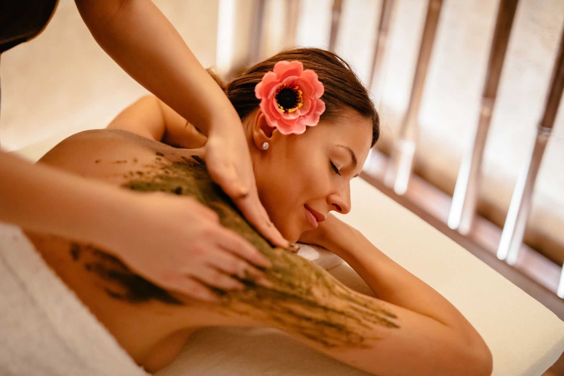 A woman is getting a massage in a spa with a flower in her hair.