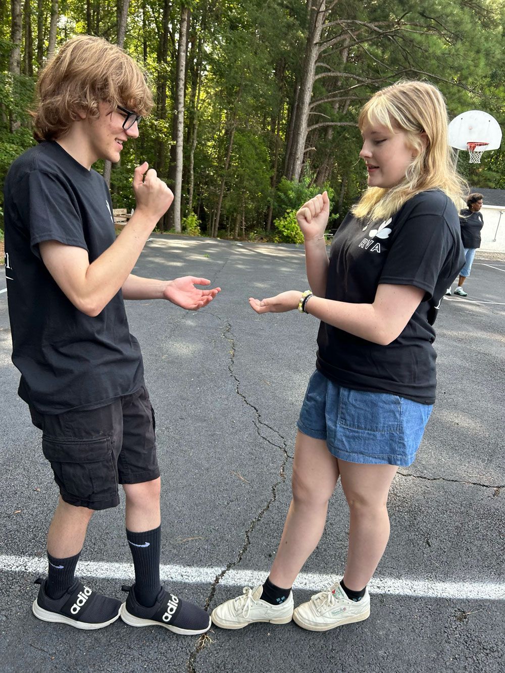 Two people playing rock-paper-scissors on a street, facing each other outdoors.