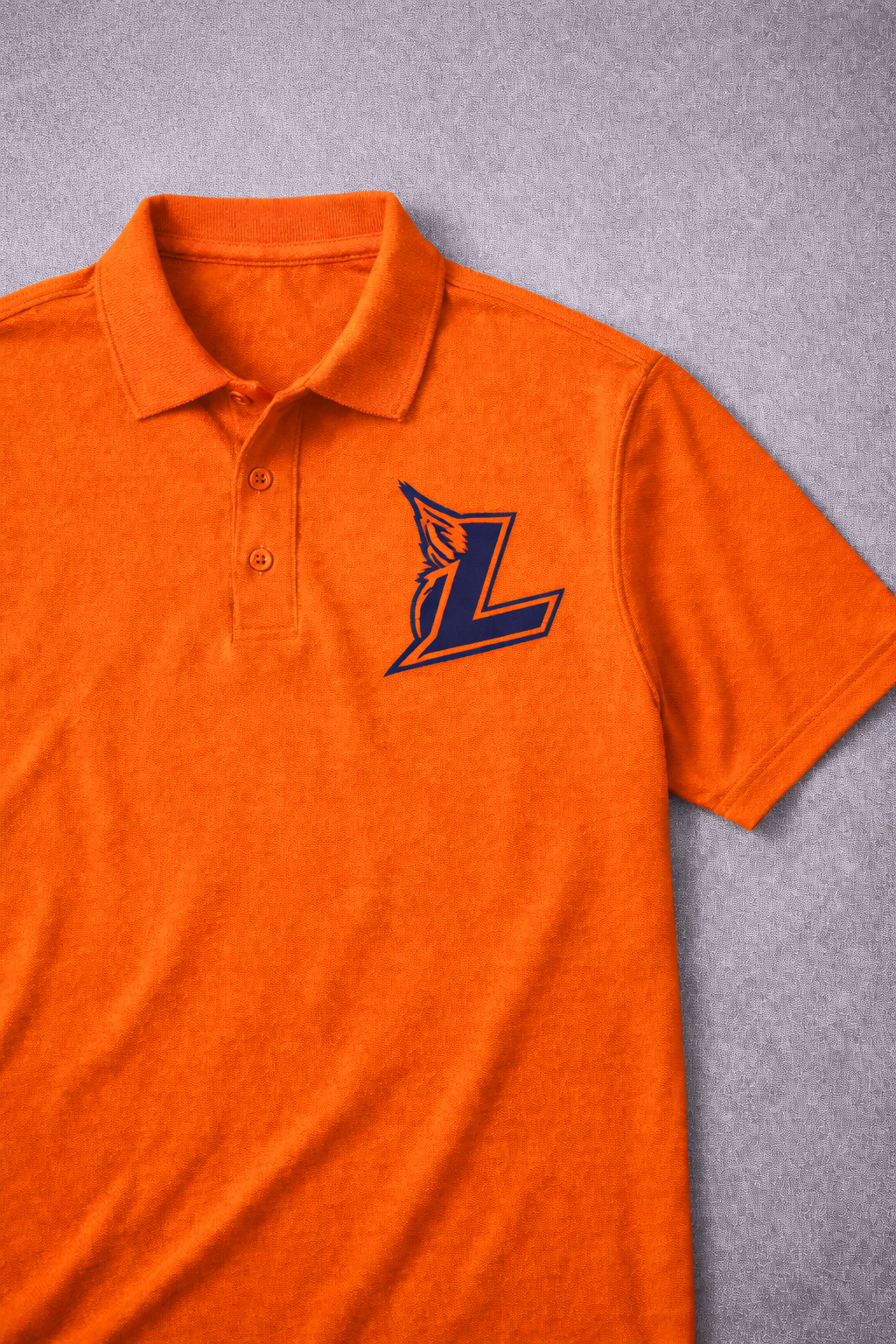 Orange polo shirt with a dark blue embroidered “L” logo on the chest, laid on a gray surface