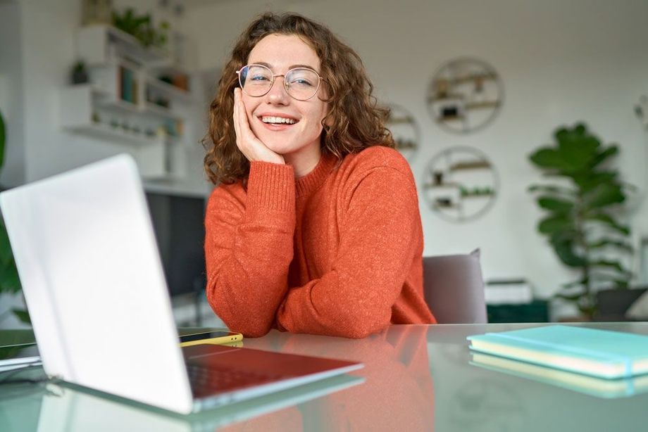 Woman smiling at a desk with a laptop in a bright home office