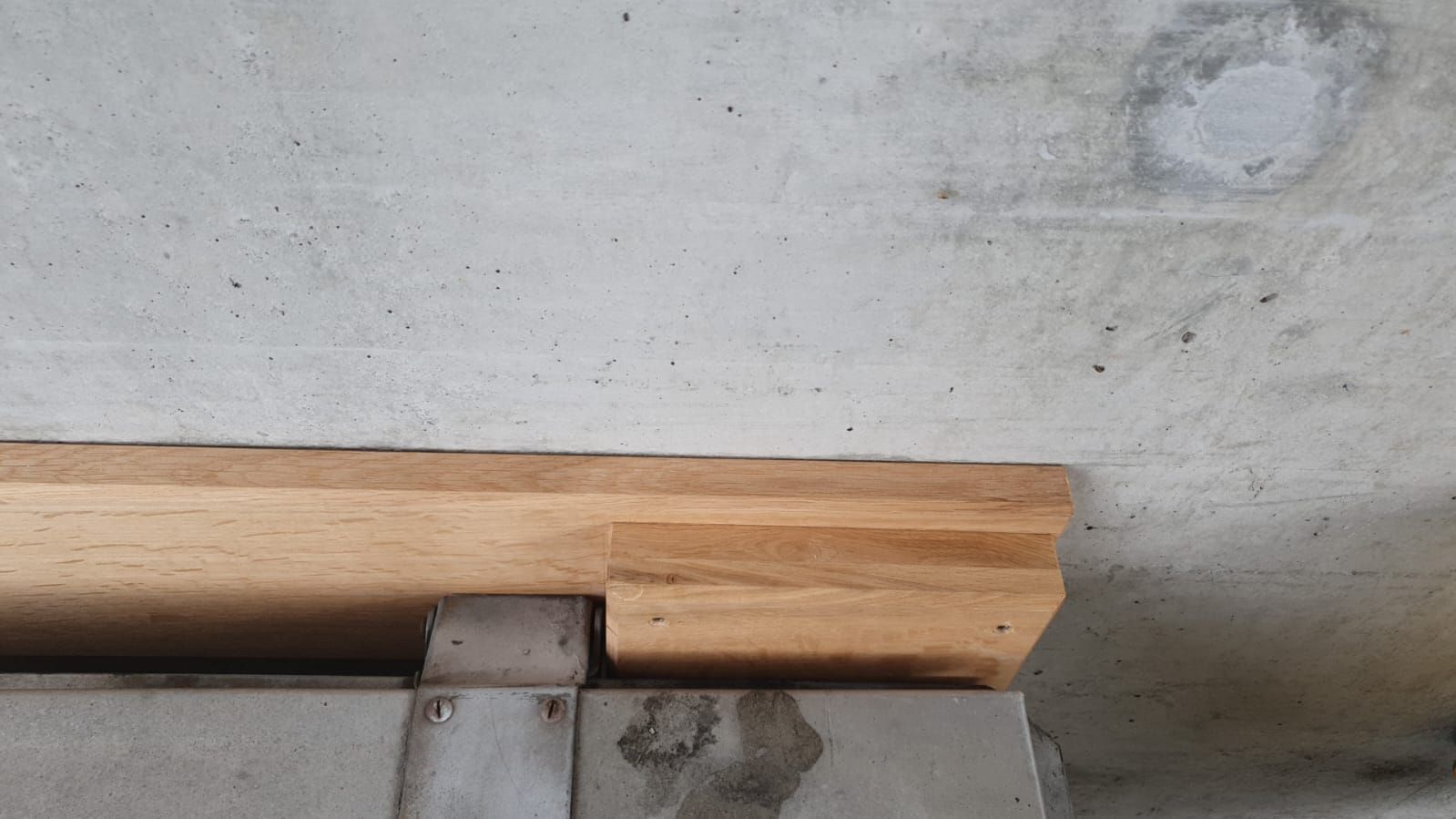 Auf einer Betonmauer liegt ein Holzbrett.