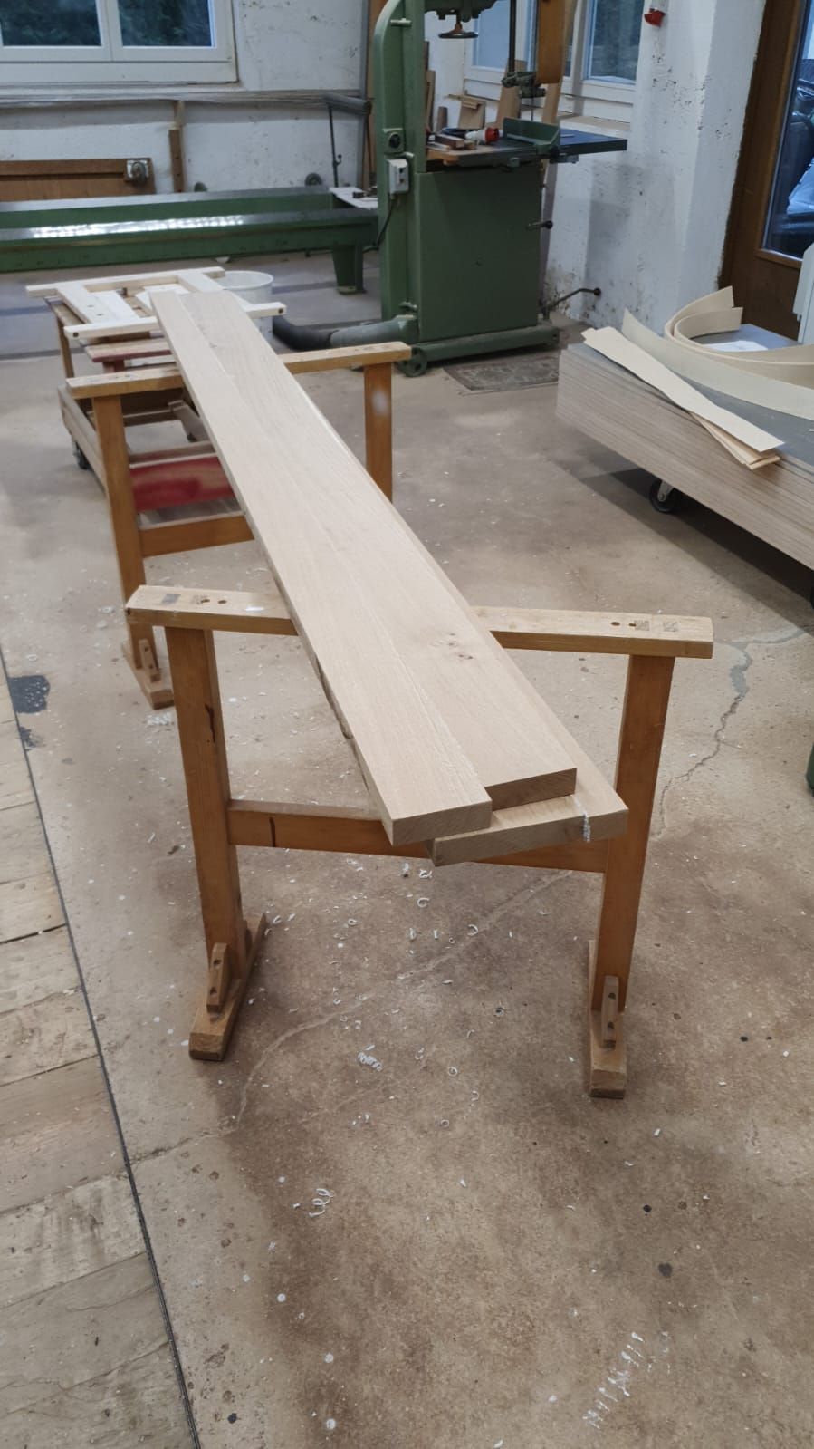 In einer Werkstatt liegt ein langes Stück Holz auf einem Holztisch.