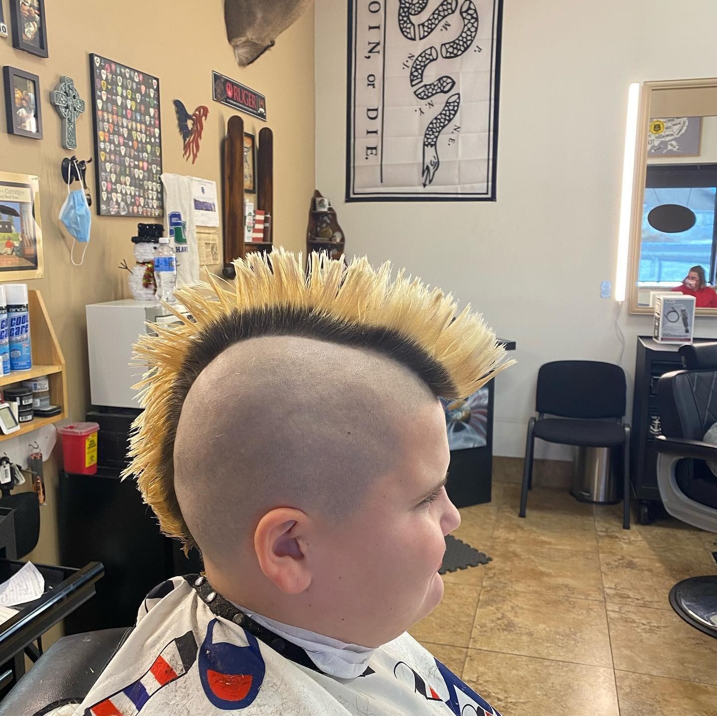 A man with a mohawk is getting his hair cut in a barber shop.