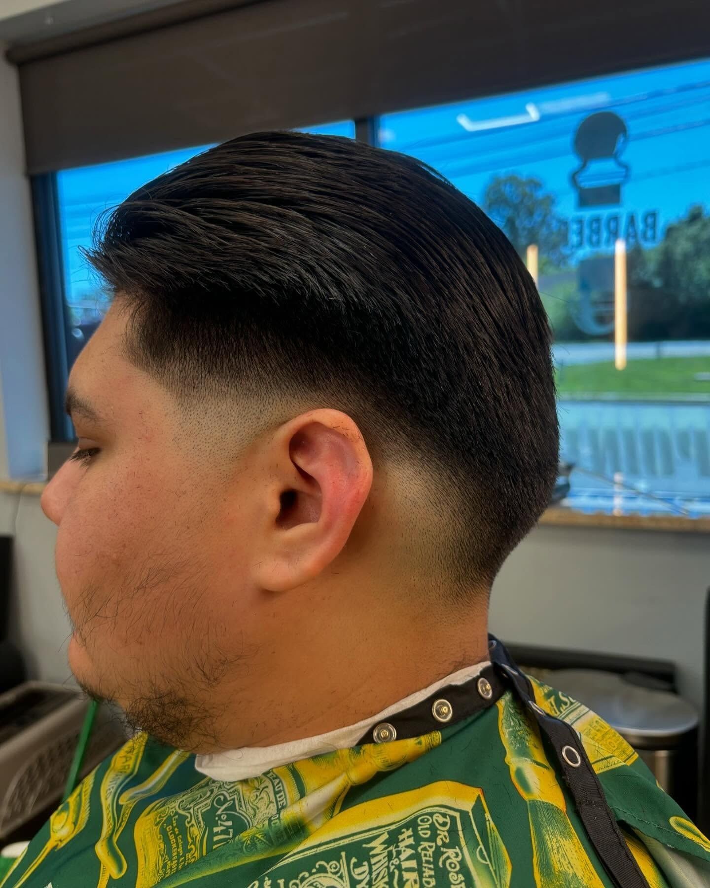 A man is getting his hair cut at a barber shop.