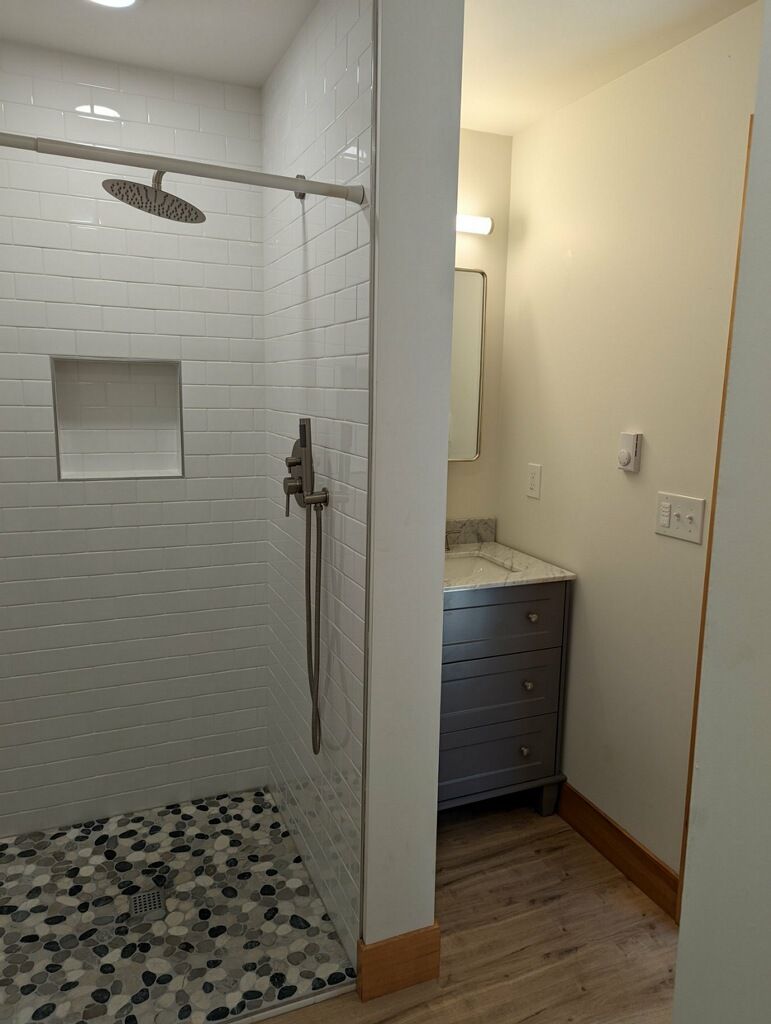 Bathroom with a tiled shower stall and vanity with a mirror.