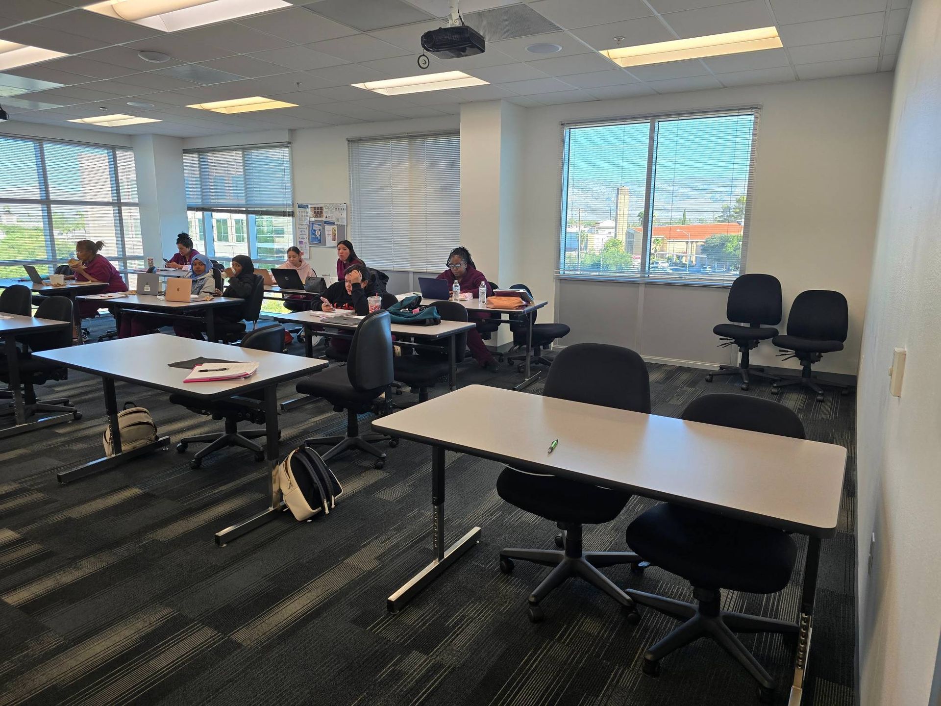 A group of people are sitting at tables in a classroom.