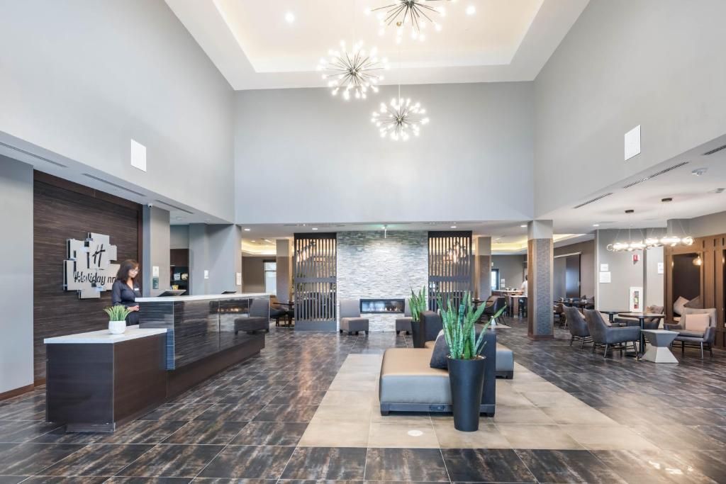 A large lobby of a hotel with a woman standing at the front desk.
