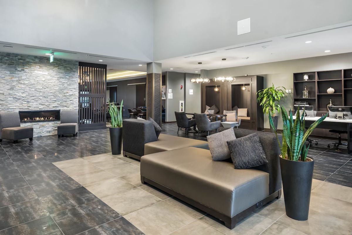 A hotel lobby with a couch , chairs , and potted plants.