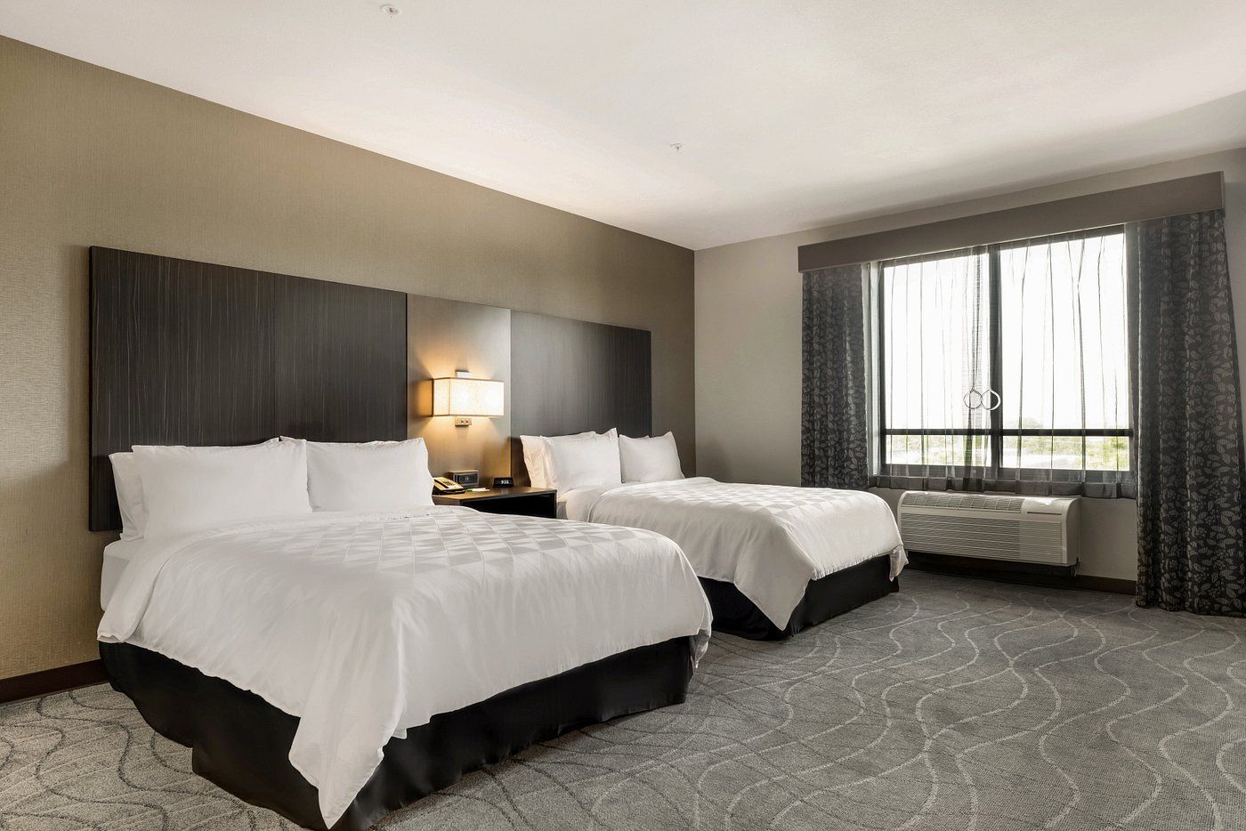 A hotel room with two beds and a large window.