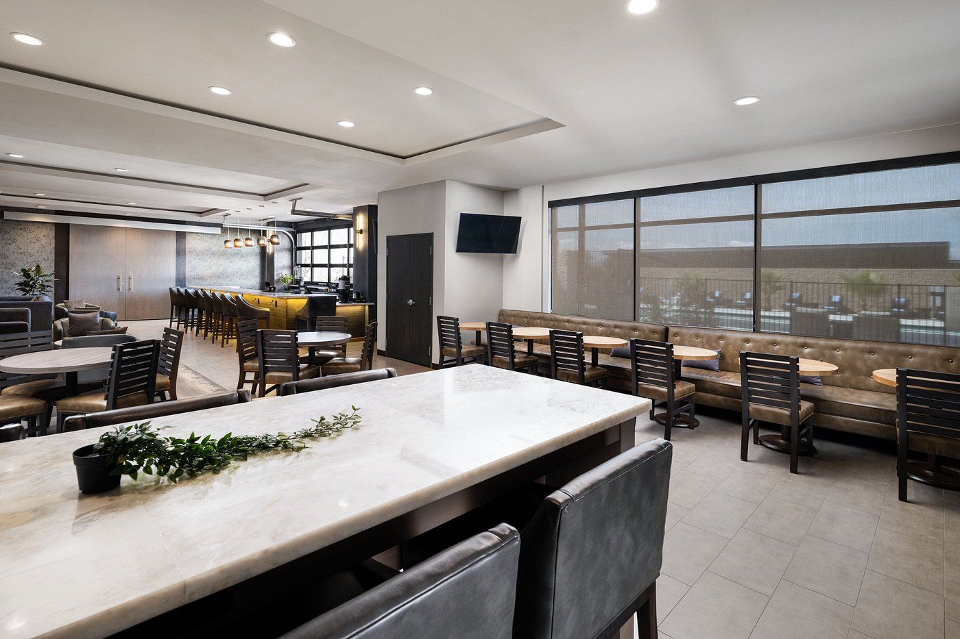 A restaurant with tables and chairs and a large table in the middle of the room.