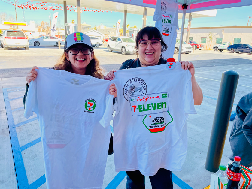 Two women are holding up a 7 eleven t-shirt