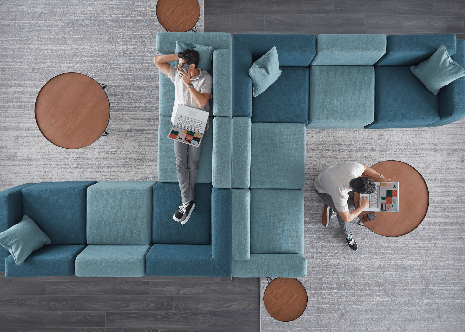 A man is laying on a couch while a woman sits at a table.