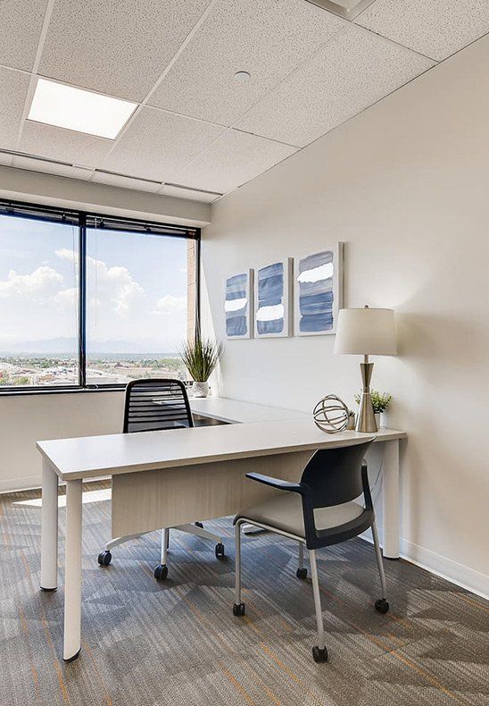 A small office with a desk and chair in front of a window.