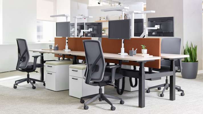 A row of desks with chairs and monitors in an office.