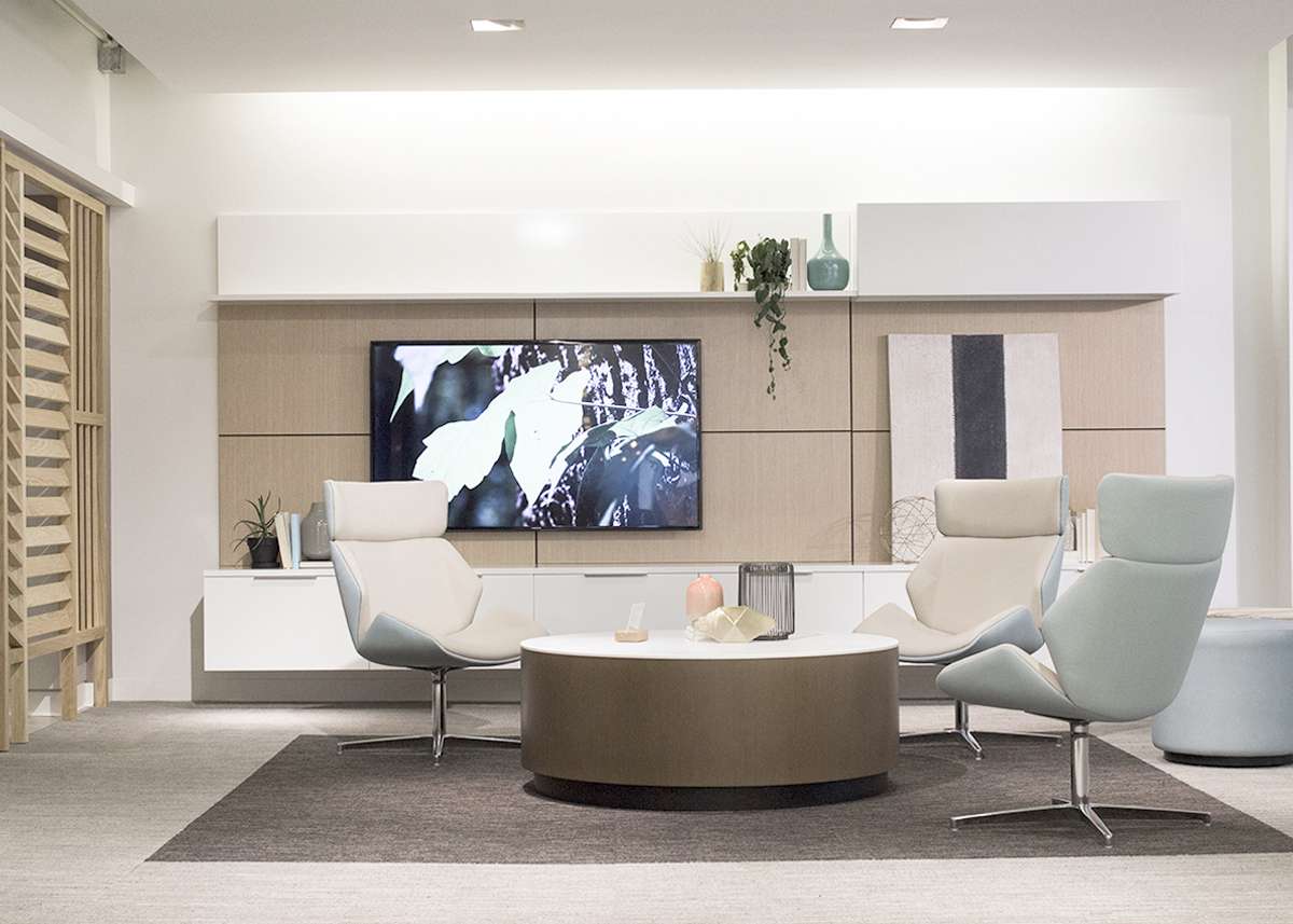 A living room with two chairs , a coffee table , and a flat screen tv.