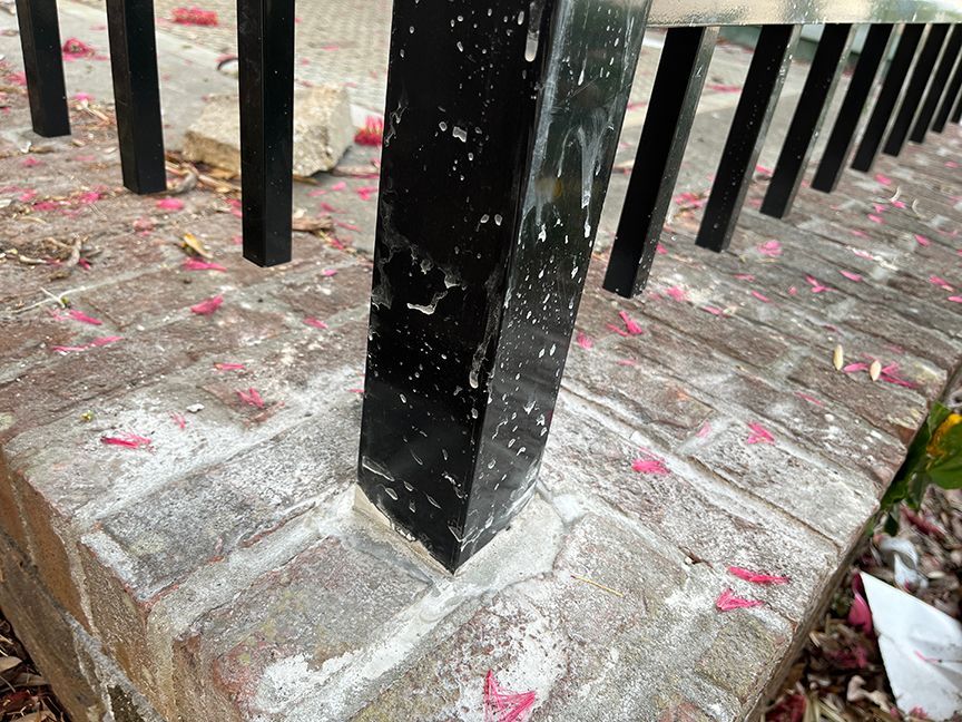 black aluminum post mounted in hole and filled with concrete