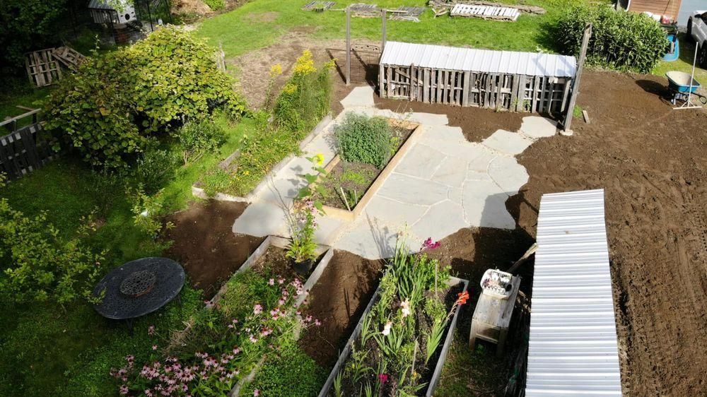 Backyard with patio, garden beds, shed, and a small greenhouse in a fenced yard