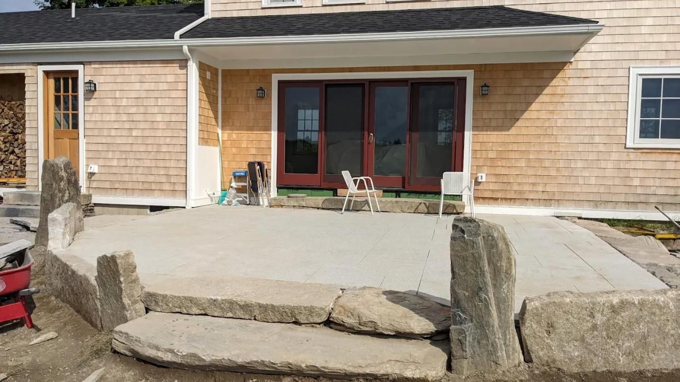 Front porch under construction with concrete steps, a wide patio, and double glass doors on a house exterior