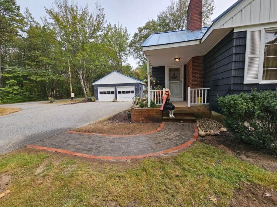 House exterior with curved brick walkway, front porch, driveway, and detached garage.