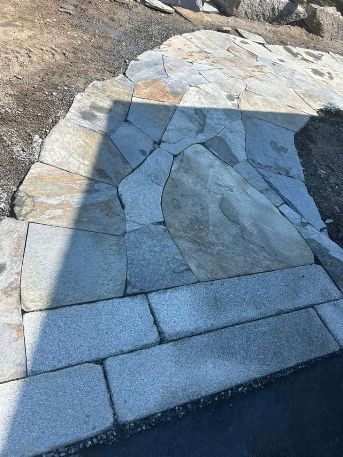 Curved stone-paved walkway with cracked flagstones and a shadow across the surface