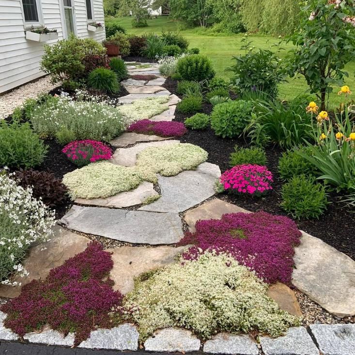 Colorful stone path through a landscaped garden with pink, white, and burgundy groundcover plants