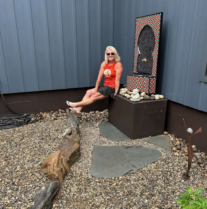 Three people and a tan dog standing outside a house near the front door