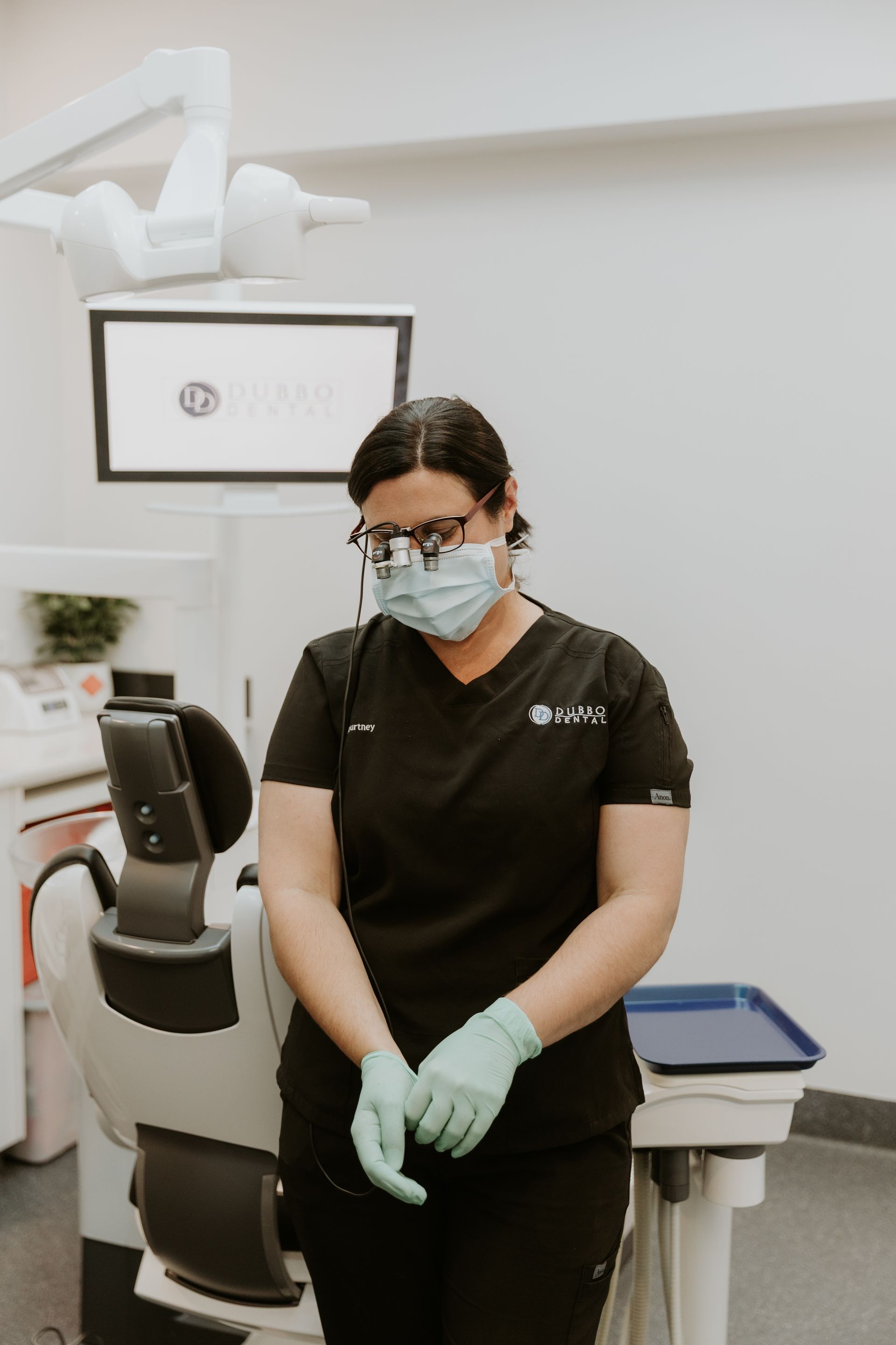 Dentist Wearing Scrubs, Mask, Glasses, and Gloves, Standing in an Exam Room — Dubbo Dental in Dubbo, NSW