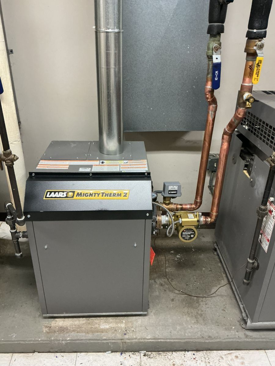 A Laars Mighty Therm boiler system with metal piping, a pump, and a vertical exhaust vent in a utility room.