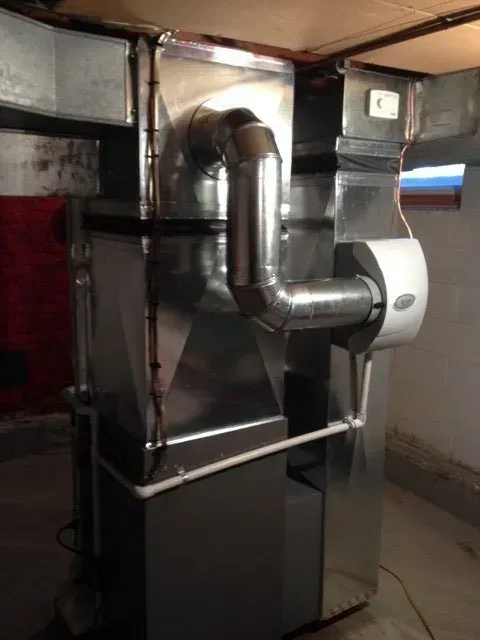 A residential HVAC furnace unit with attached metal ductwork and a humidifier installed in a basement.