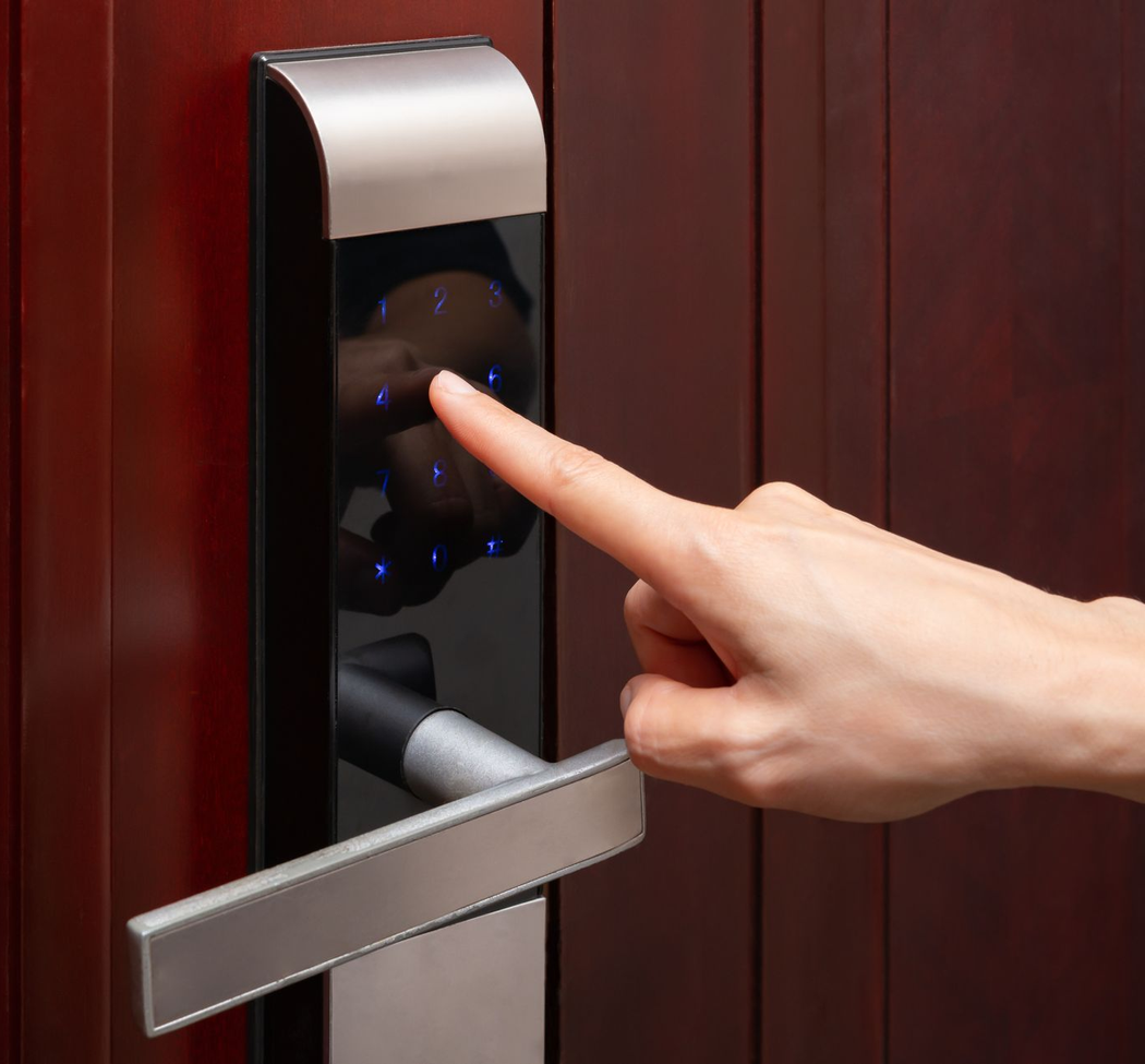 Finger touching a dark biometric door lock on a wooden door