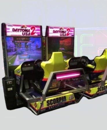 Two Daytona USA 2 arcade racing game machines, yellow and black, with screens displaying a race track.