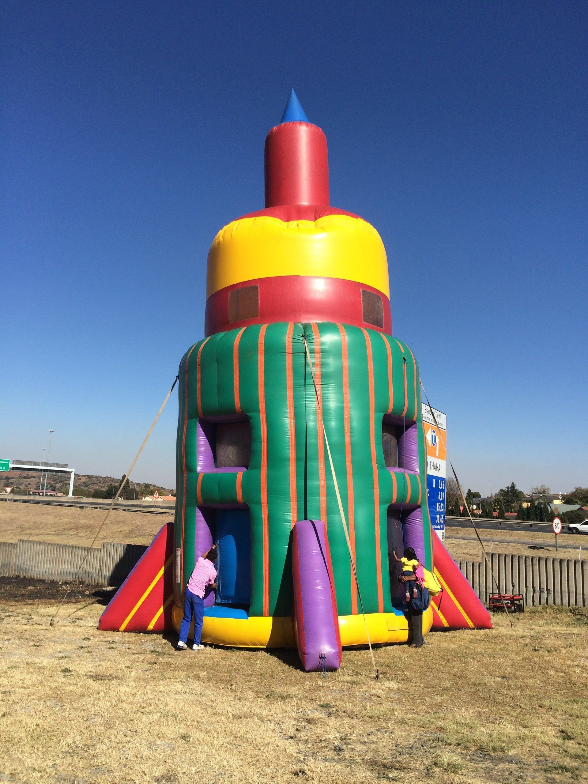 Inflatable rocket ship bouncer with children playing outside.