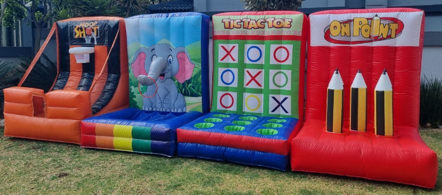Four inflatable carnival game stations set up on green grass.