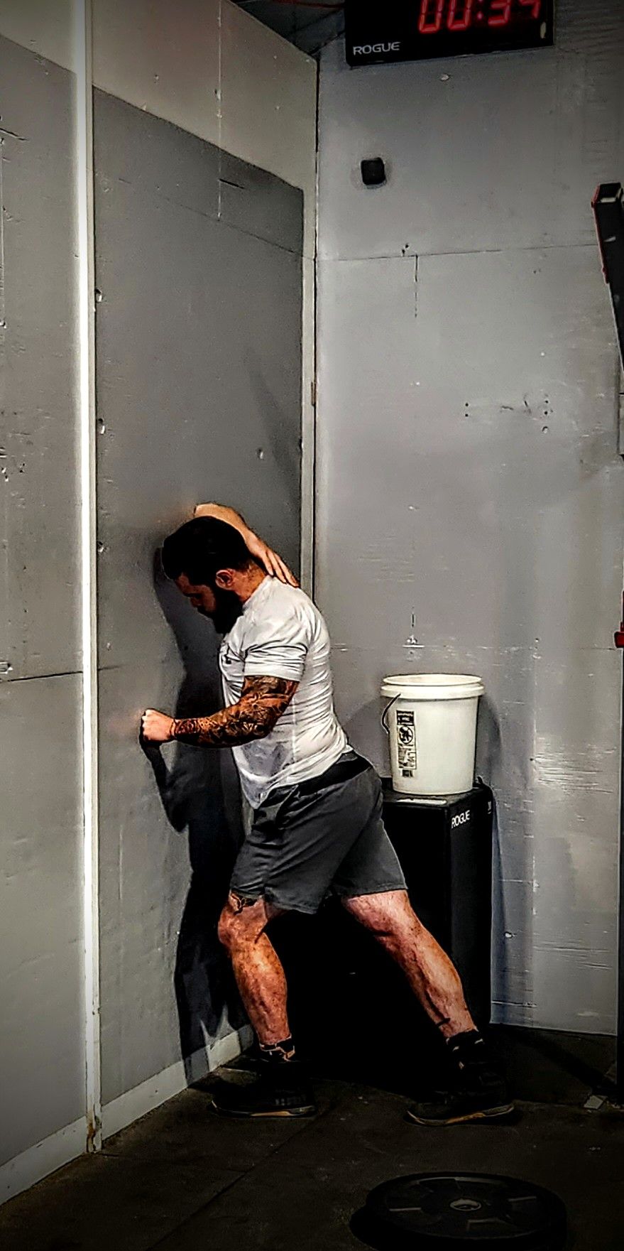 A man is leaning against a wall in a gym.