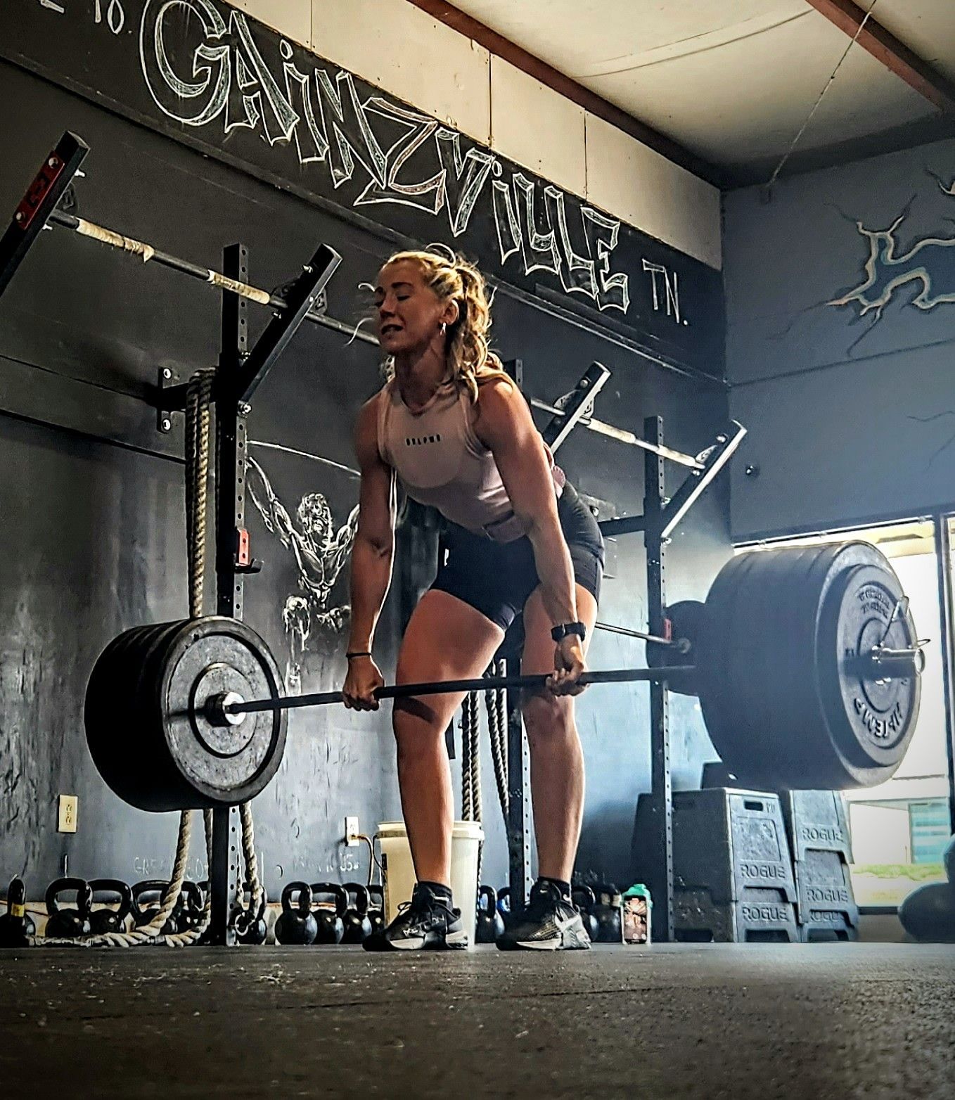 A woman is lifting a barbell in a gym